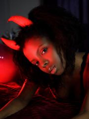 Pretty black girl Sukki T unveils her hairy pussy during a striptease on a bed