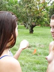 Pretty naked lesbians are standing naked and showing their bodies outdoors