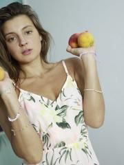 Nice girl Melena Tara holds a couple of peaches while sporting a butt plug