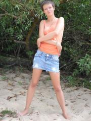 Sexy teen with short hair exposes her tiny tits and bald pussy on a beach